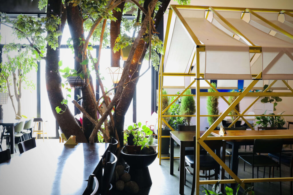 식물과 파빌리온 테이블이 어우러져 있는 채광 좋은 릴869 카페의 실내 모습