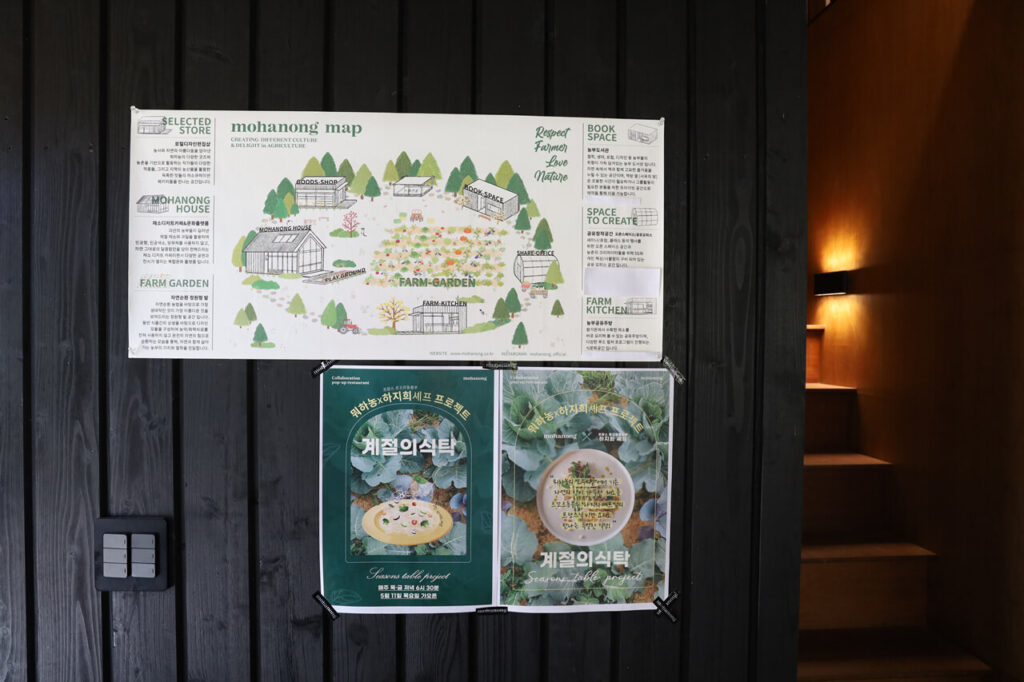 검은색 세로 결의 목재 벽면에 붙어 있는 애견 동반 카페 뭐하농 하우스(Mohanong house)의 시설 배치와 메뉴 안내 포스터