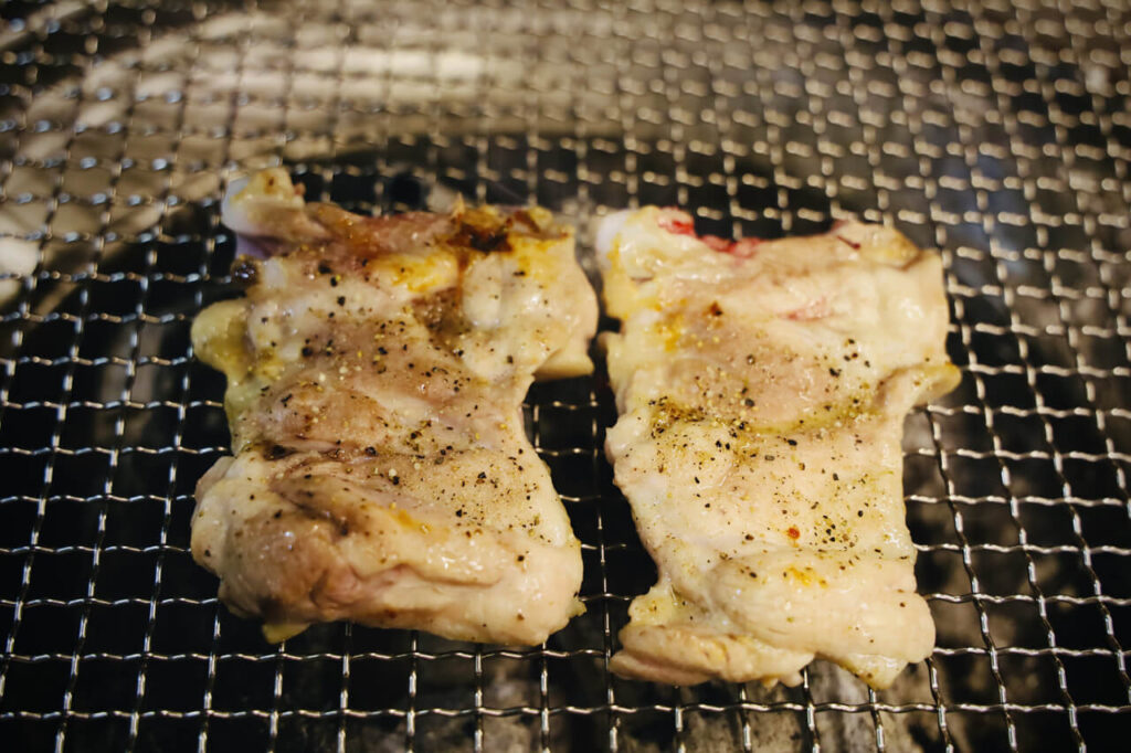 숯불 위 철판에 놓인 후추가 묻은 샘토 명물 닭갈비의 마카 소금구이 닭갈비